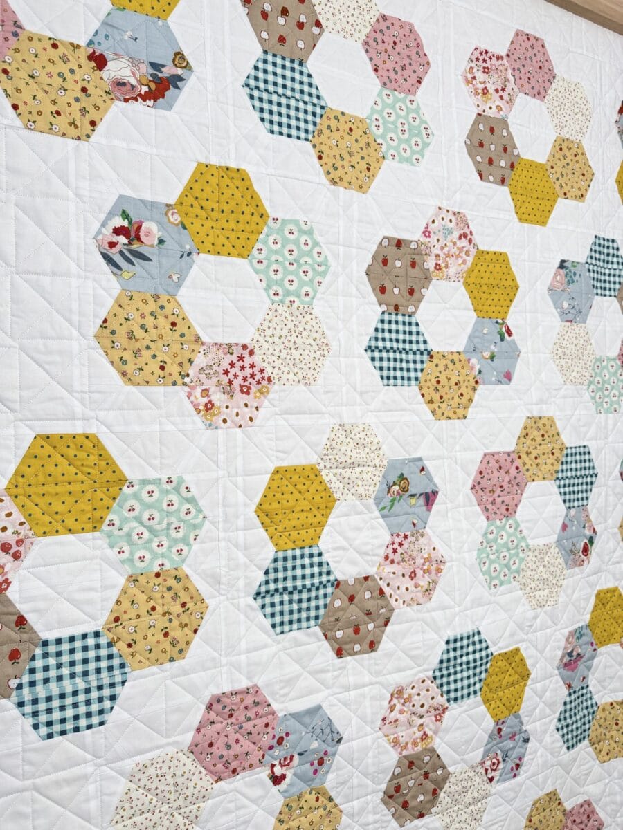 Angled view of several scrappy half-hexagon flower blocks in the Hexie Blooms quilt