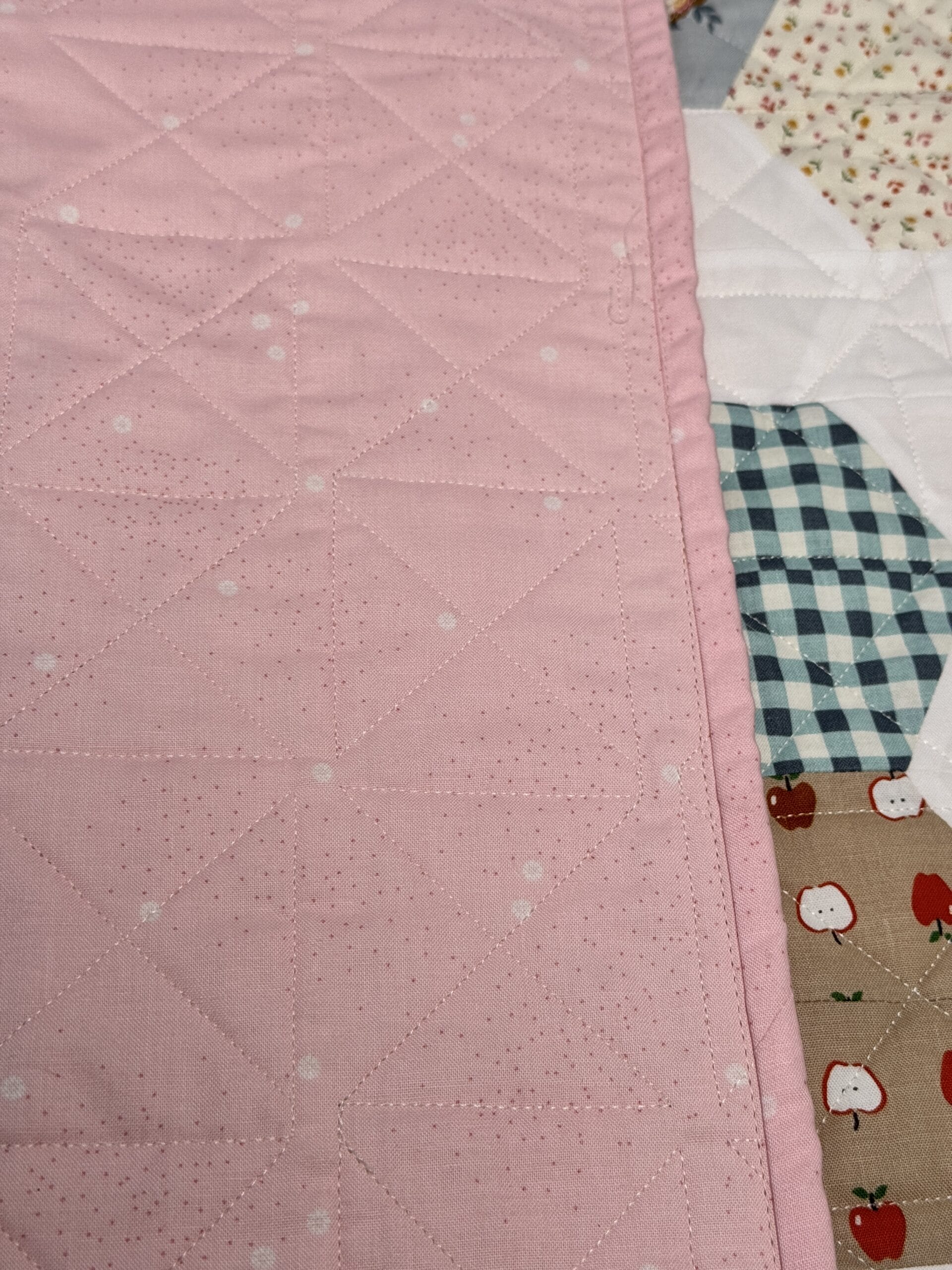 Hexie Blooms quilt with one edge flipped over to show the pink daisy backing