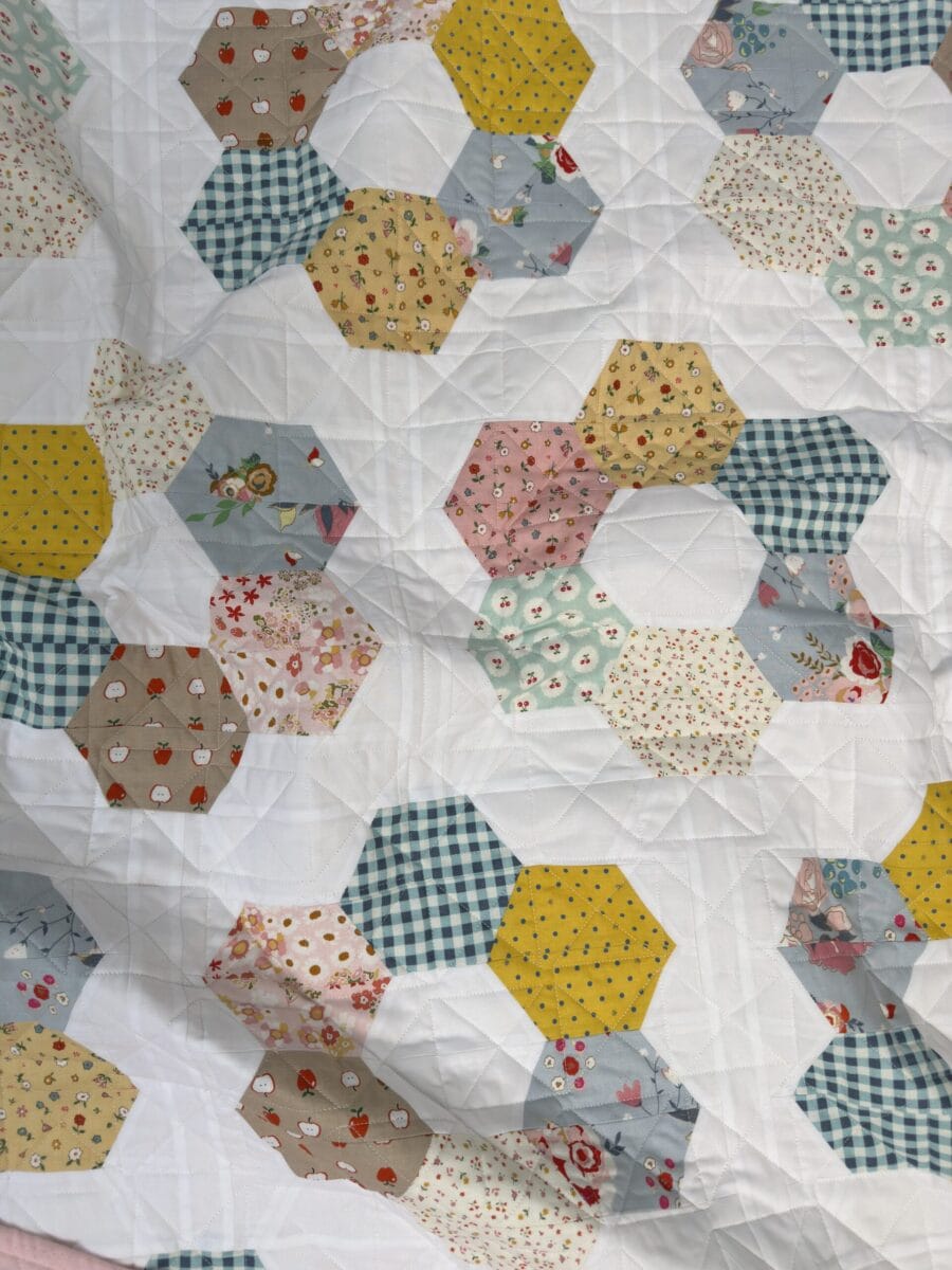Hexie Blooms quilt loosely arranged on the floor showing its colorful scrappy design