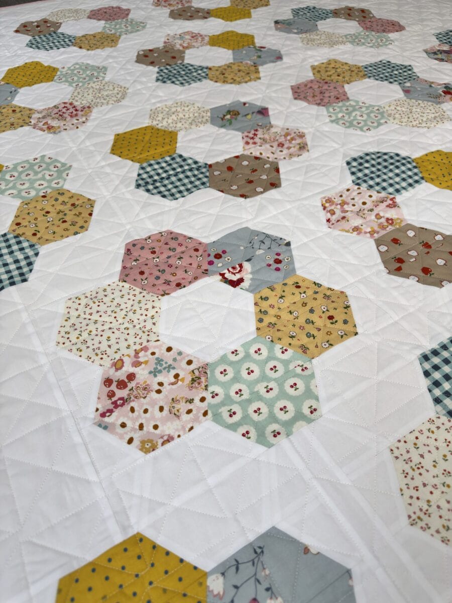 Close-up of the Hexie Blooms quilt showing colorful half-hexagon blocks and geometric quilting