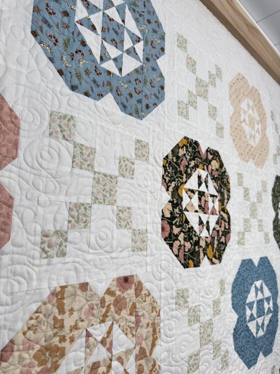 Close-up of the Gardenia quilt showing floral longarm quilting across the white background