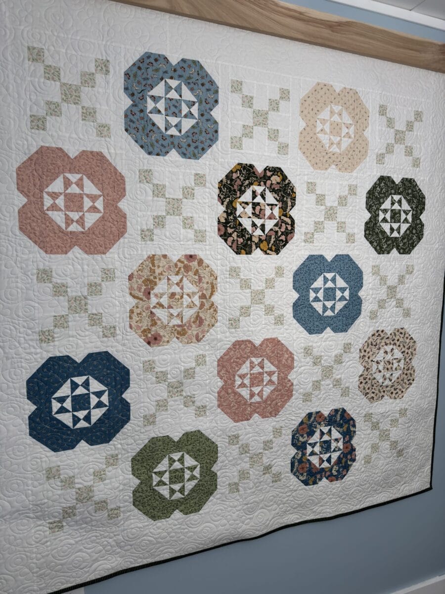 Finished Gardenia quilt made with Petalush fabrics hanging on a wall
