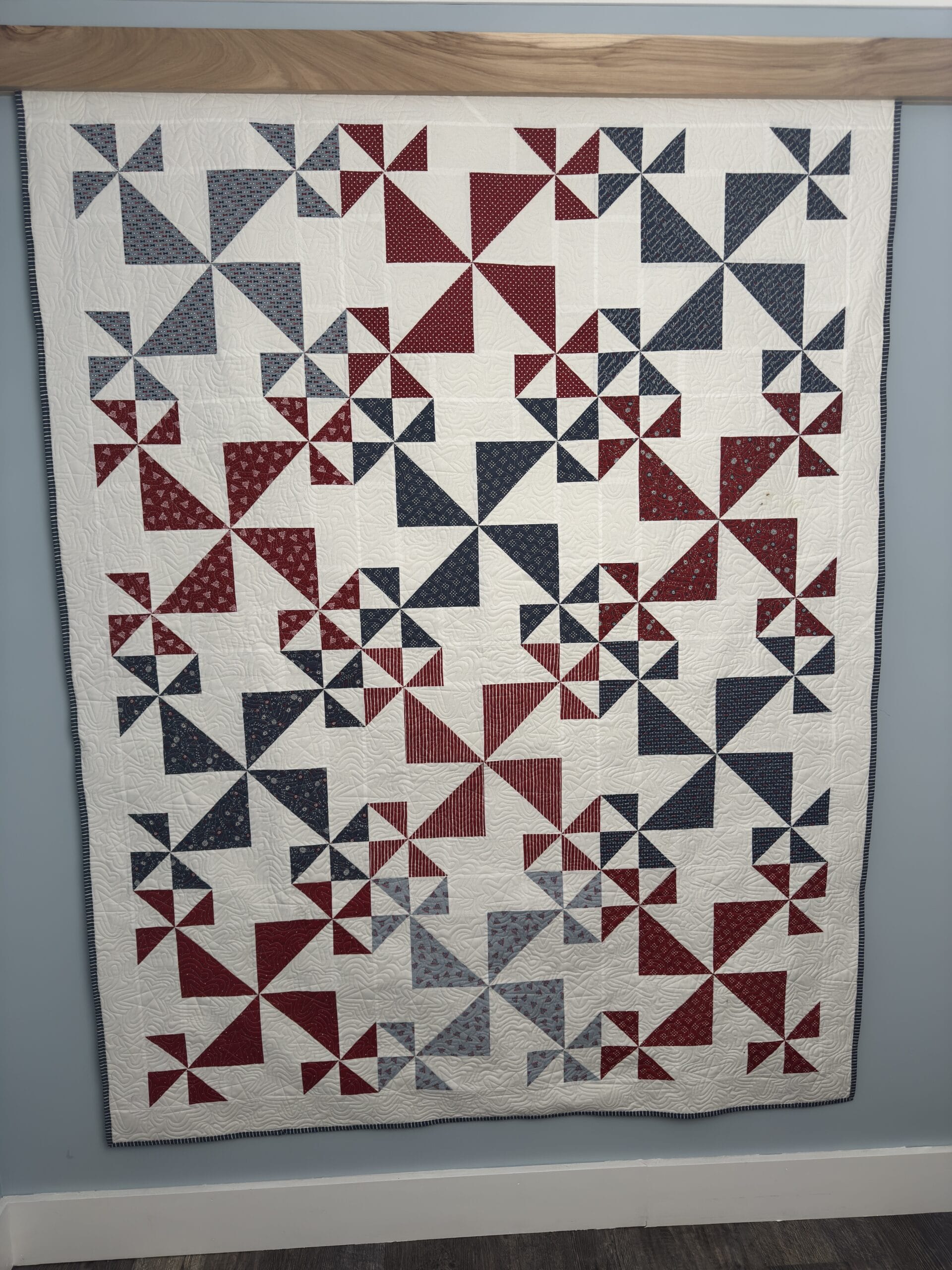 DIY Compression quilt hanger holding a patriotic quilt