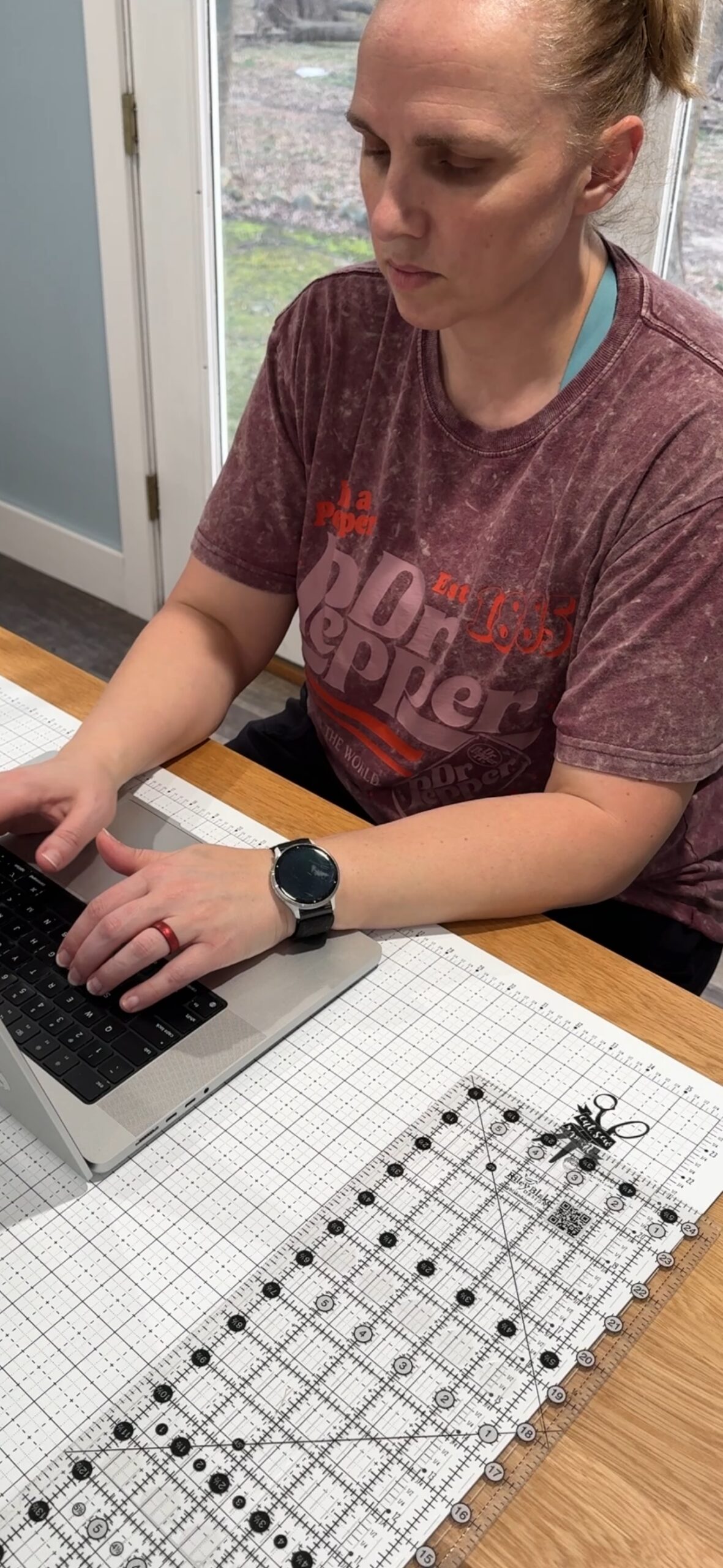 Nicole typing on a laptop at her cutting desk.